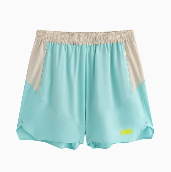 Men's loose grey workout shorts with elastic waist and lace-up fly on a gym floor.