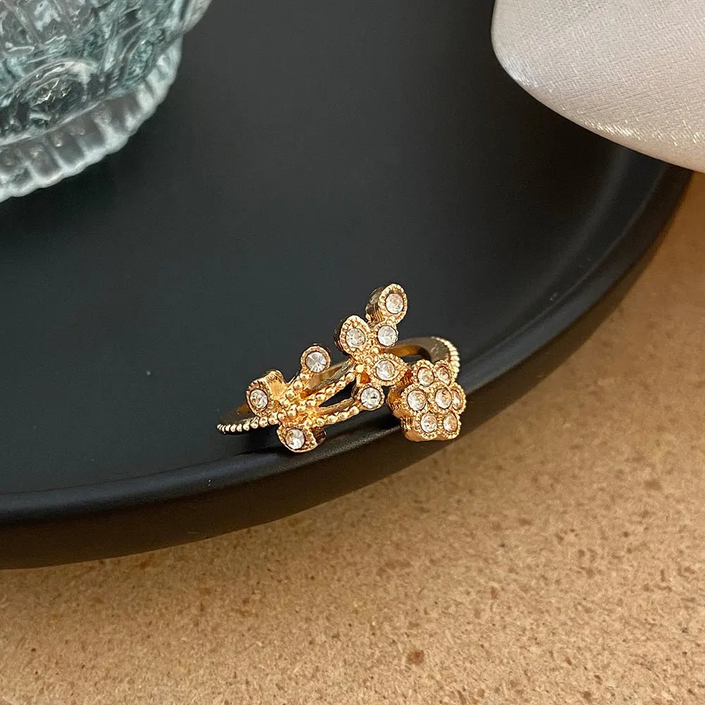 Close-up of a women's open ring with detailed floral leaf engraving, shown in gold colour finish.