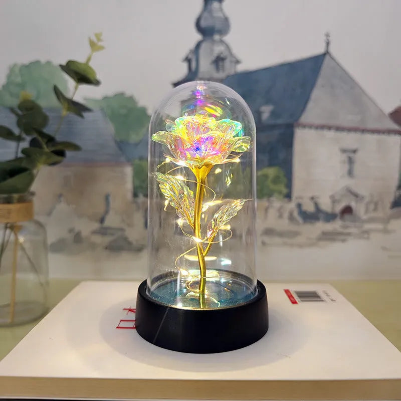 Small decorative night lamp with glass cover and plastic flowers, showing coloured light illumination.