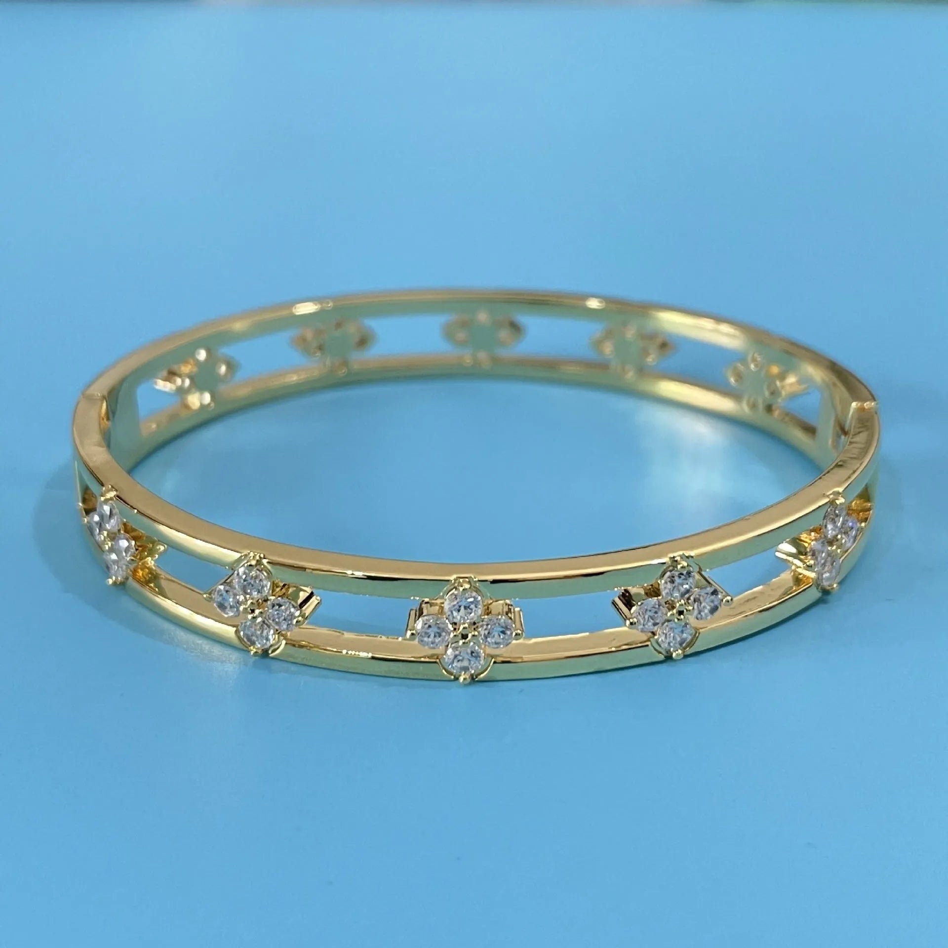 Women's hollow bracelet with a four-leaf clover zircon charm on an adjustable band, shown in gold and silver finishes.