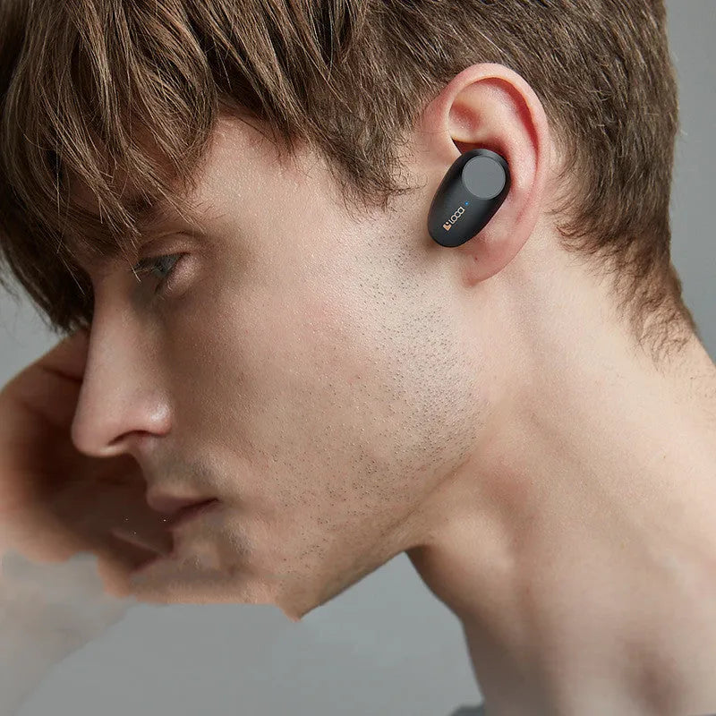 Black wireless Bluetooth headset with charging stand on a table.