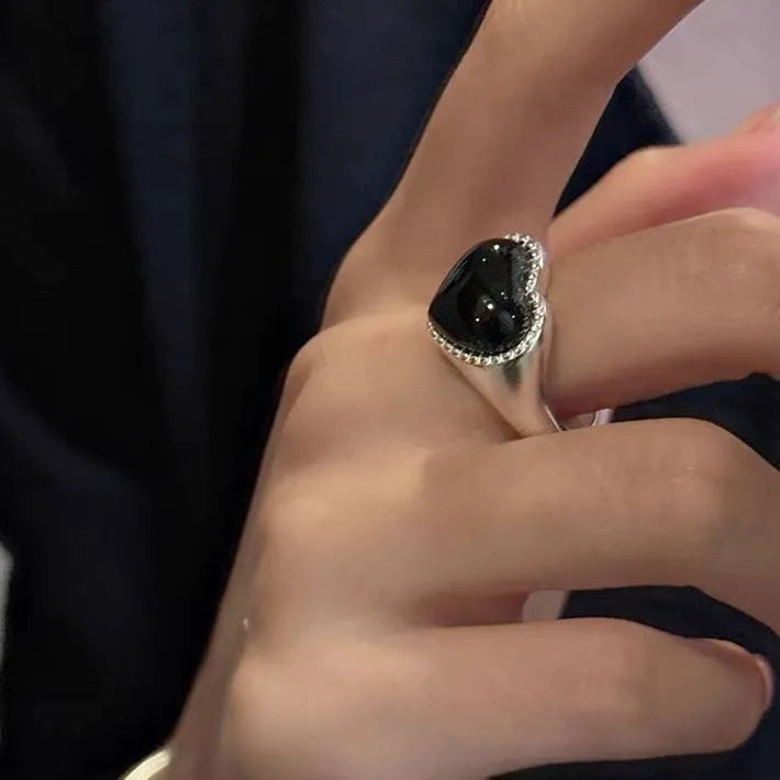 Sterling silver adjustable ring with black agate heart design on model's hand