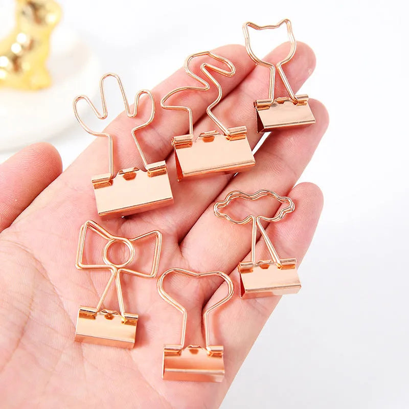 Gold plated decorative paper clip in a choice of flamingo, love, cloud, cat, cactus, or bow designs on a white background.