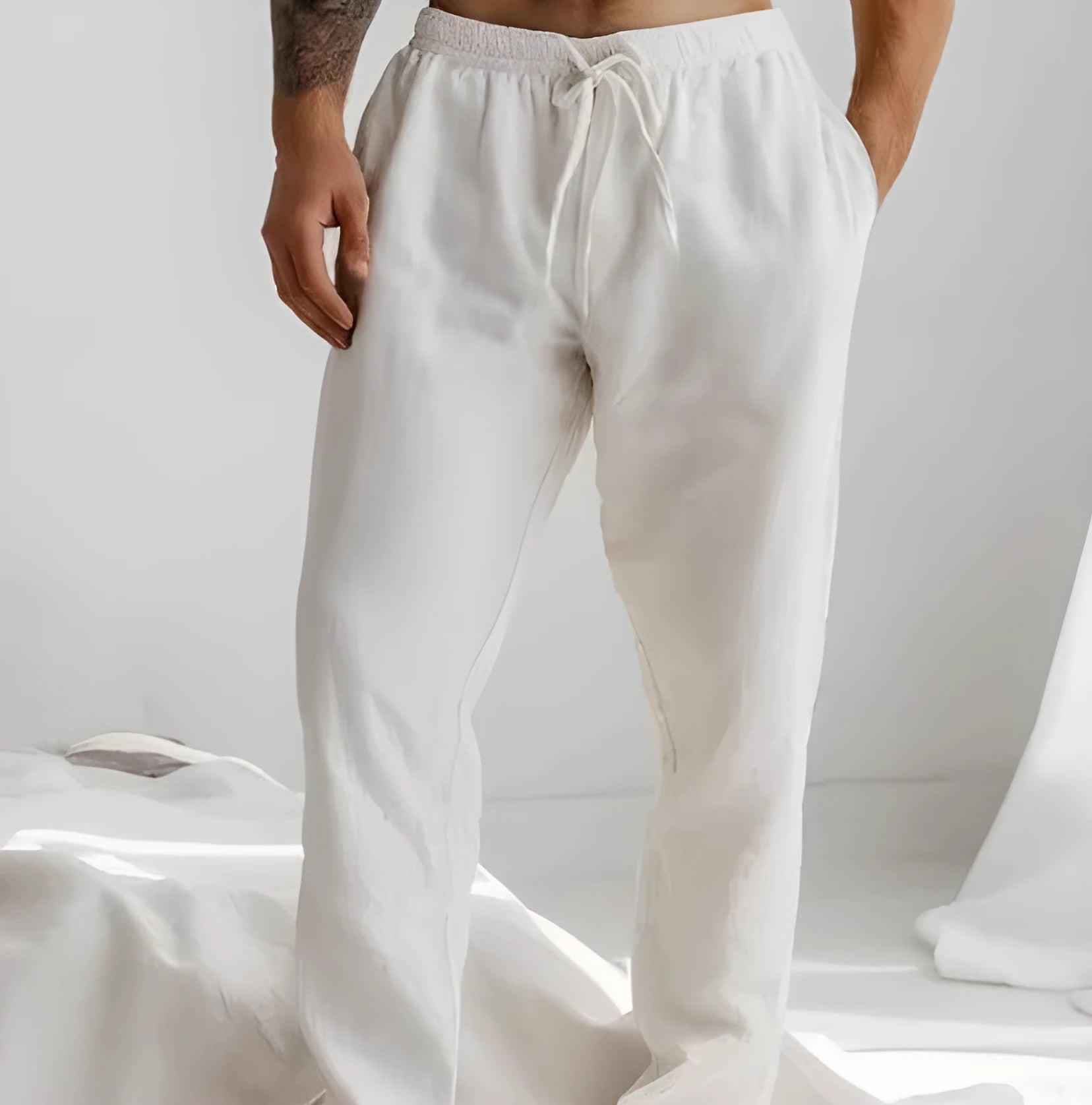 Men's light grey loose-fit cotton linen summer trousers with an elastic drawstring waist on a plain background.