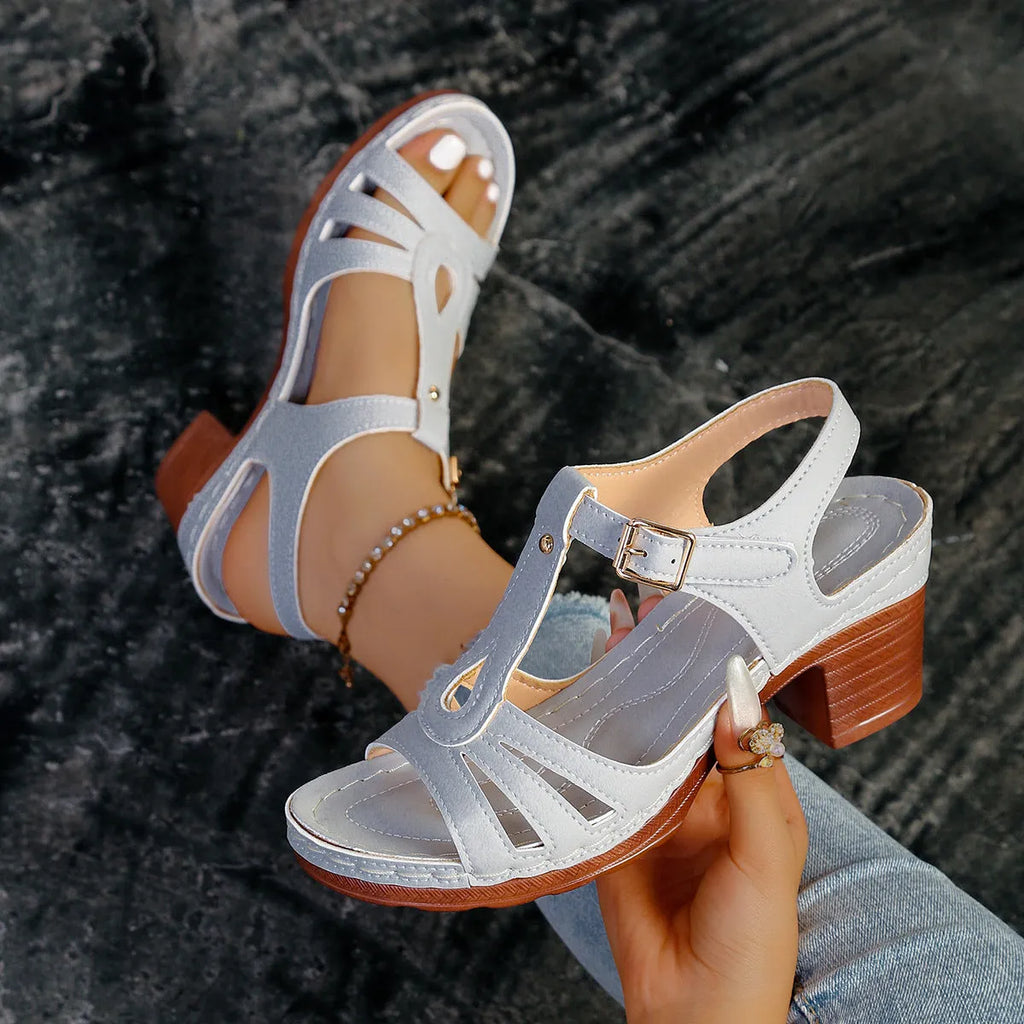 Women's black peep toe wedge sandals with a buckle fastening on a wooden floor.