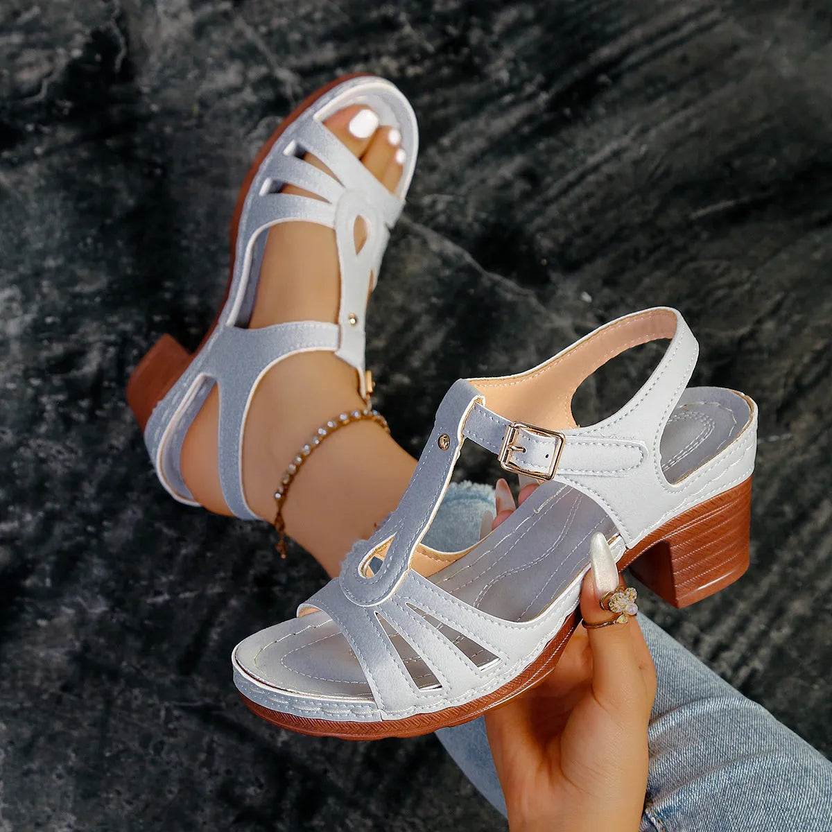 Women's black peep toe wedge sandals with a buckle fastening on a wooden floor.