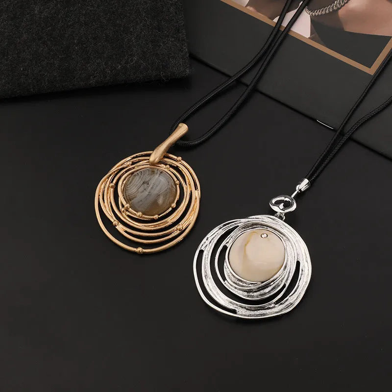 Gold geometric alloy pendant on a brown snakeskin wax rope chain necklace laid flat.