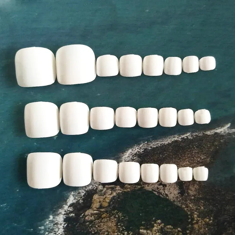 White false nail set with starry sky pattern and adhesive glue for at-home application.