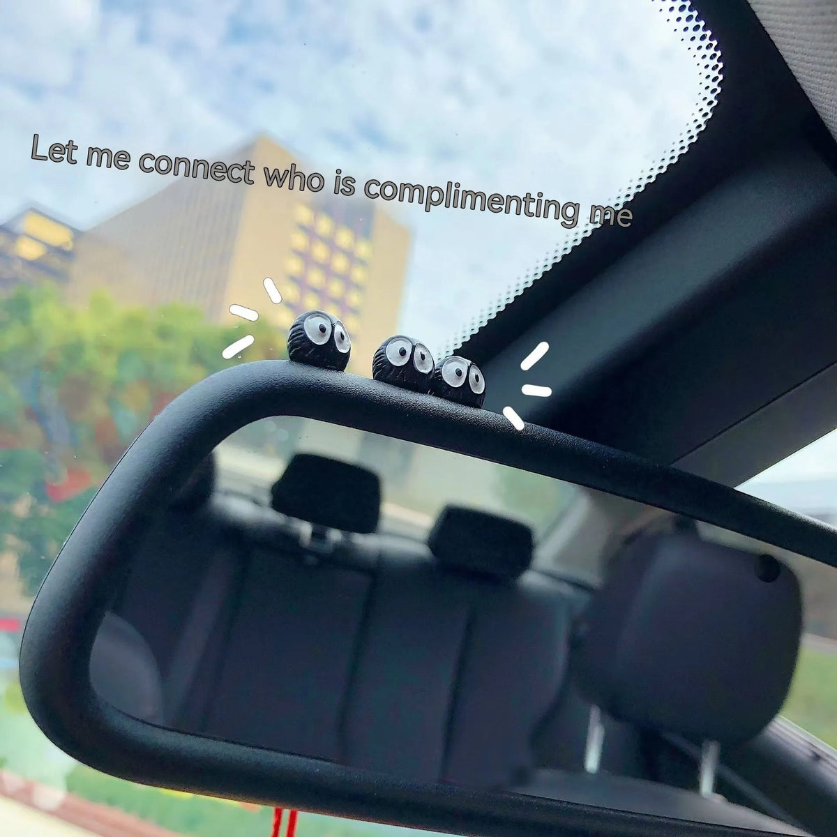 Small black resin coal ball cartoon decoration on a car dashboard.