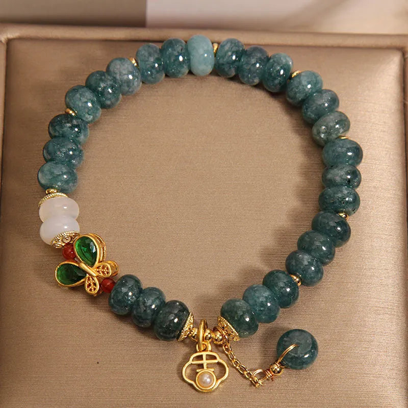 Close-up of a women's bracelet with blue water jade abacus beads, white agate, alloy inlay, and a butterfly clasp.