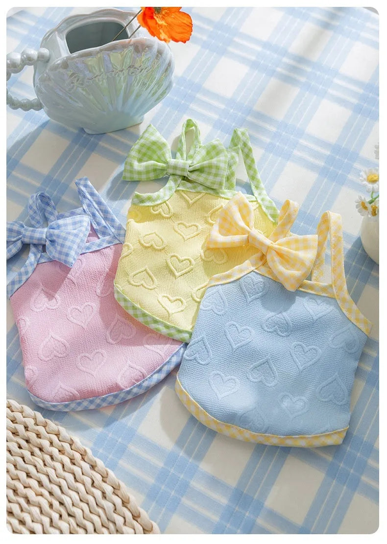 Small dog wearing a blue heart texture vest with bow suspenders and matching hairband