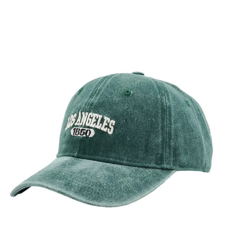 Retro style peaked cap with embroidered distressed letters on the front, shown in beige colour.