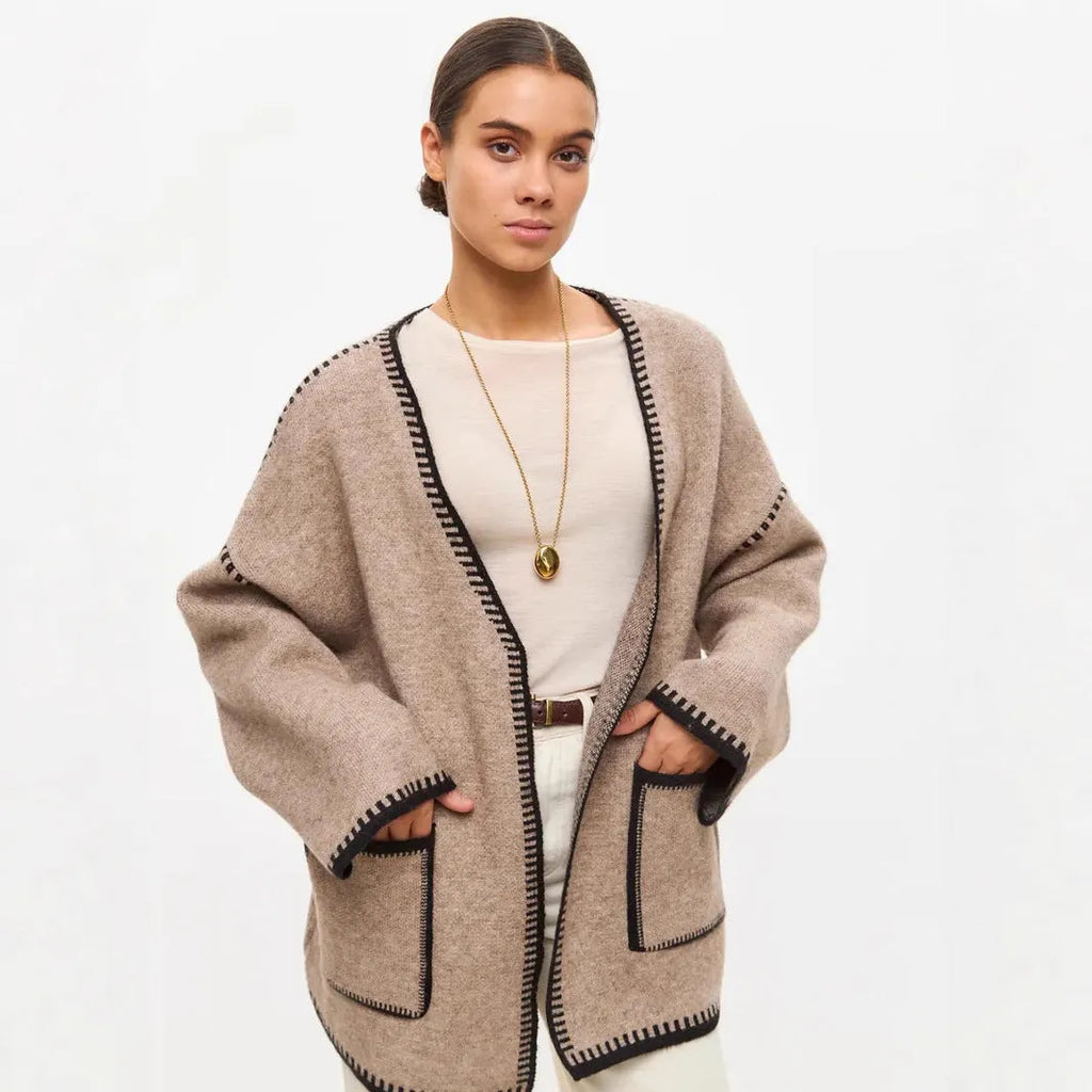 Loose grey knitted cardigan with lace-up front ties on a hanger.