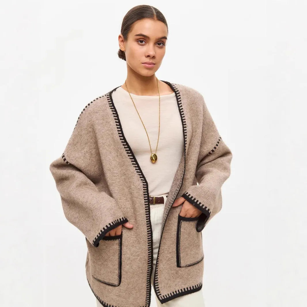 Loose grey knitted cardigan with lace-up front ties on a hanger.