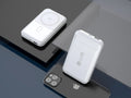 Magnetic wireless charging power bank with folding stand open, showing colour options on a table.