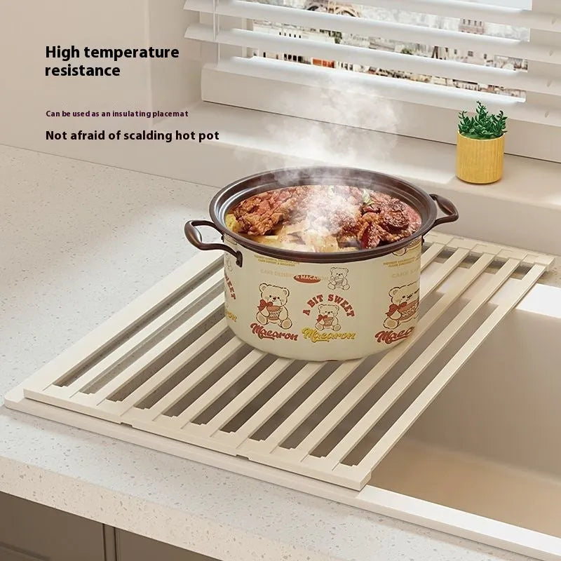 Milky white foldable stainless steel kitchen draining rack shown unfolded next to a sink.