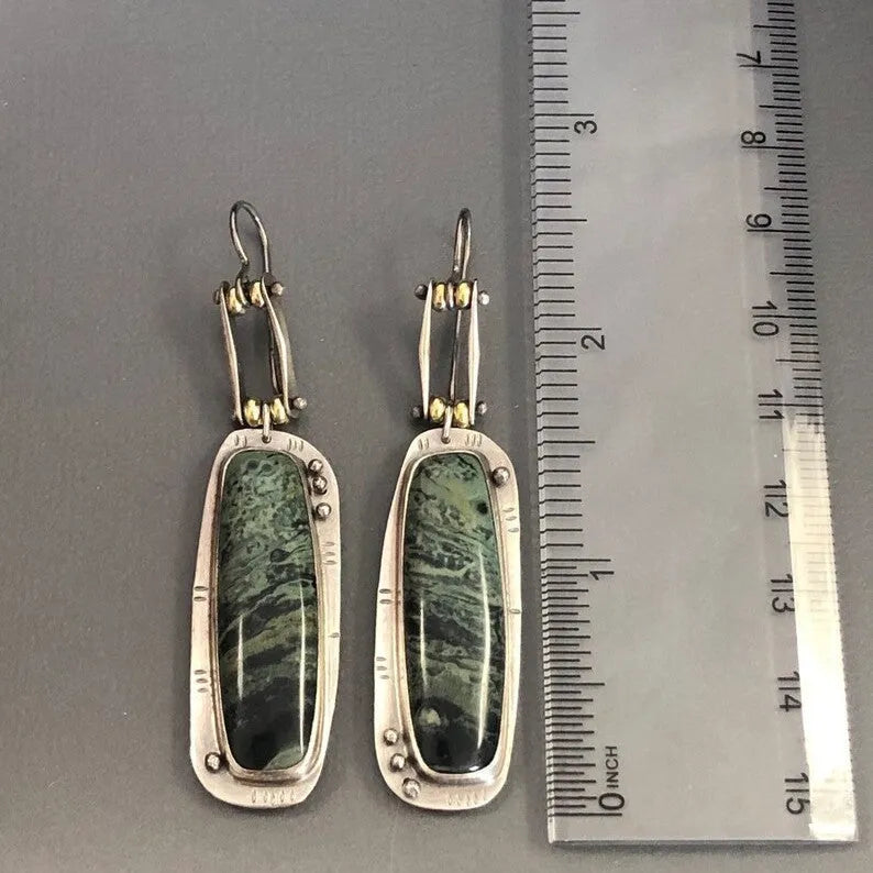 Close-up of simple geometric drop earrings with a two-colour marble pattern finish.