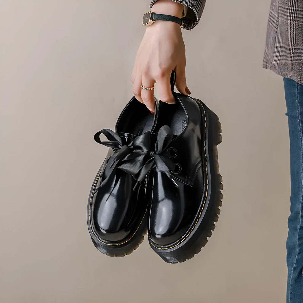 Women's black leather shoes with thick sole, cross strap, and ribbon lacing closure