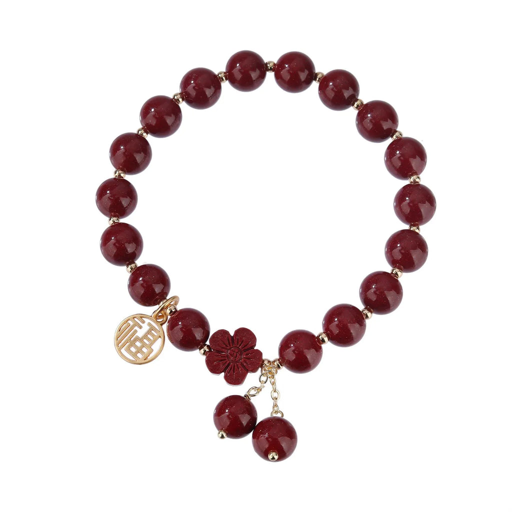 Women's cinnabar bracelet with purple gold sand finish and traditional fu character charm with tassel detailing
