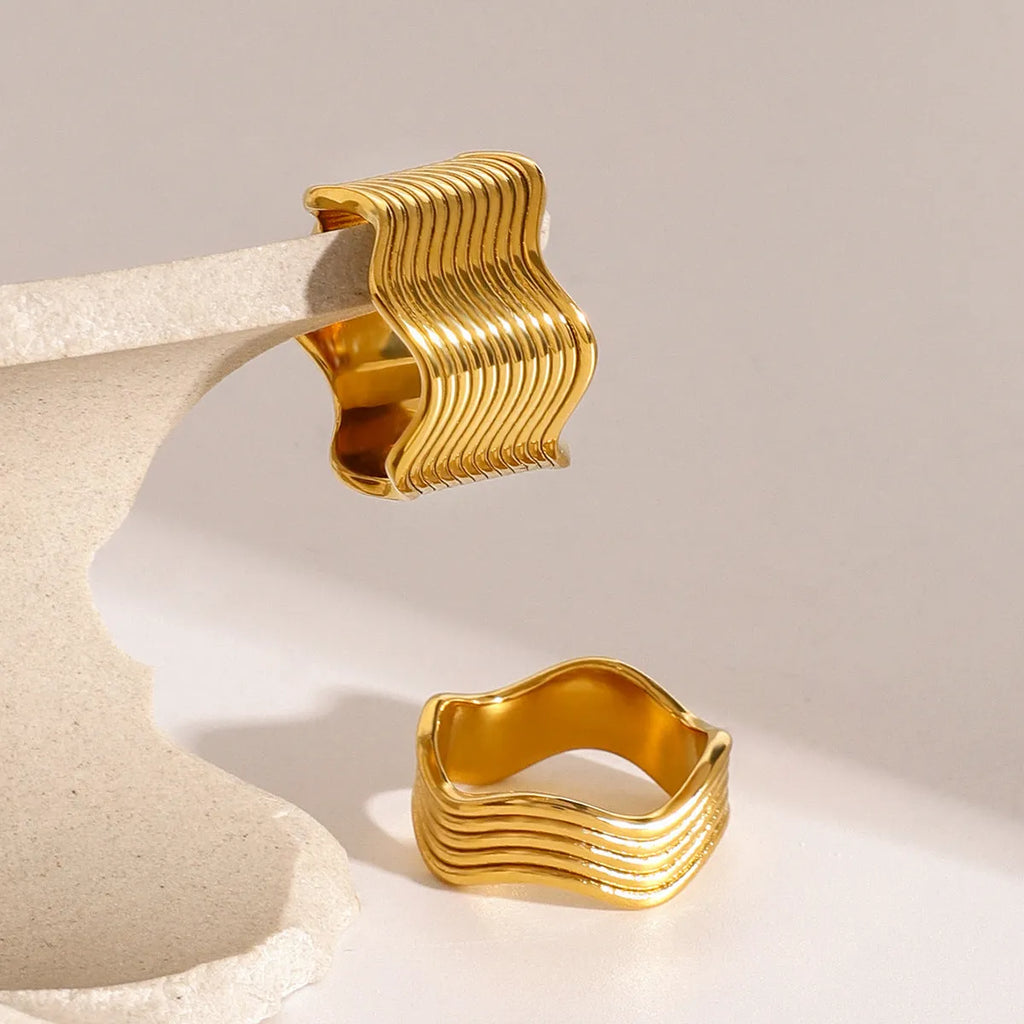 Stainless steel wide band ring with a geometric wave pattern, shown in silver and gold electroplated finishes.