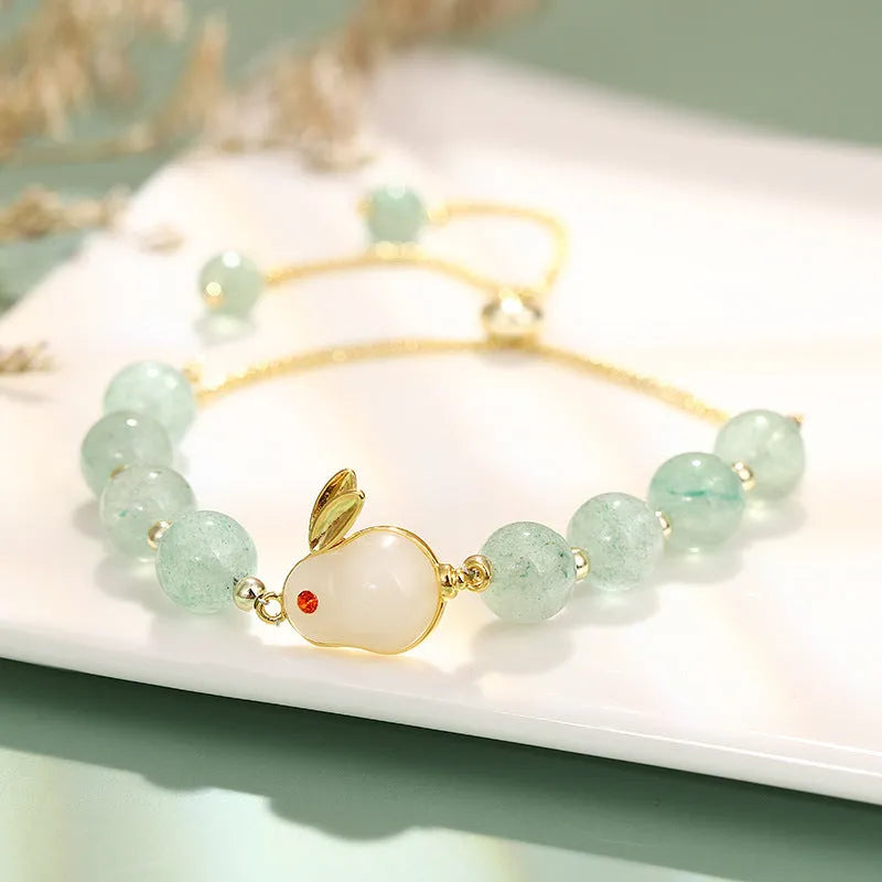 Green aventurine and strawberry quartz rabbit charm bracelet on a copper and gold chain.