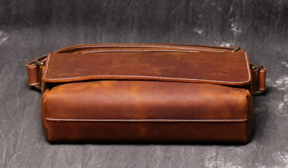 Vintage brown leather mens messenger bag with a flap opening and adjustable shoulder strap.