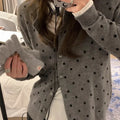 Women's grey dot patterned knitted cardigan with crochet flower detail on sleeve.