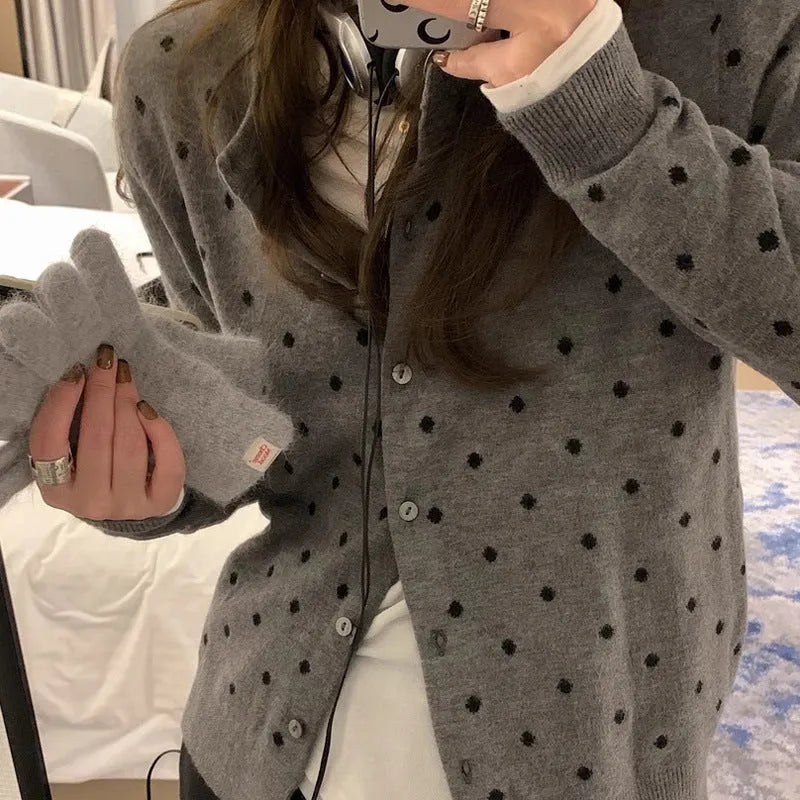 Women's grey dot patterned knitted cardigan with crochet flower detail on sleeve.