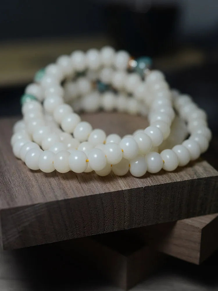 White jade bodhi seed bracelet with 108 flat round beads on a wrist.