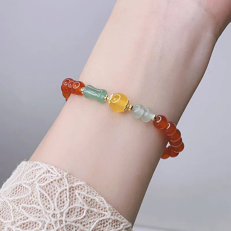 Close-up of a manually crafted red agate bracelet with Lucky Bag and dragon designs on a wrist.