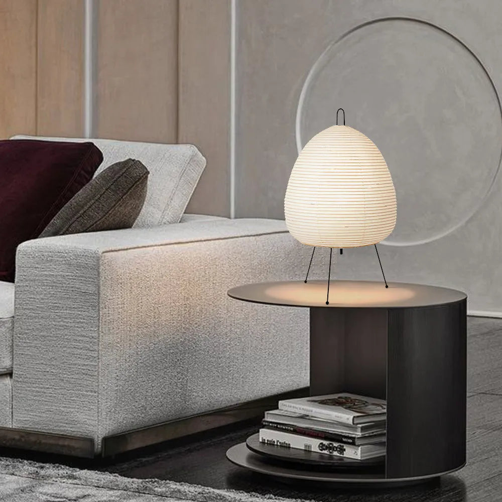 Japanese style table lamp with a white rice paper lantern shade and a silver aluminium base on a wooden table.
