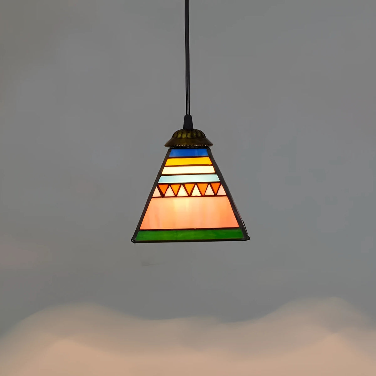 Vintage styled pendant light with a coloured glass shade hanging from an iron ceiling plate.