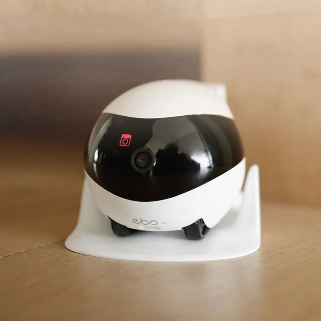 White smart home mobile surveillance robot camera next to its automatic charging docking station.