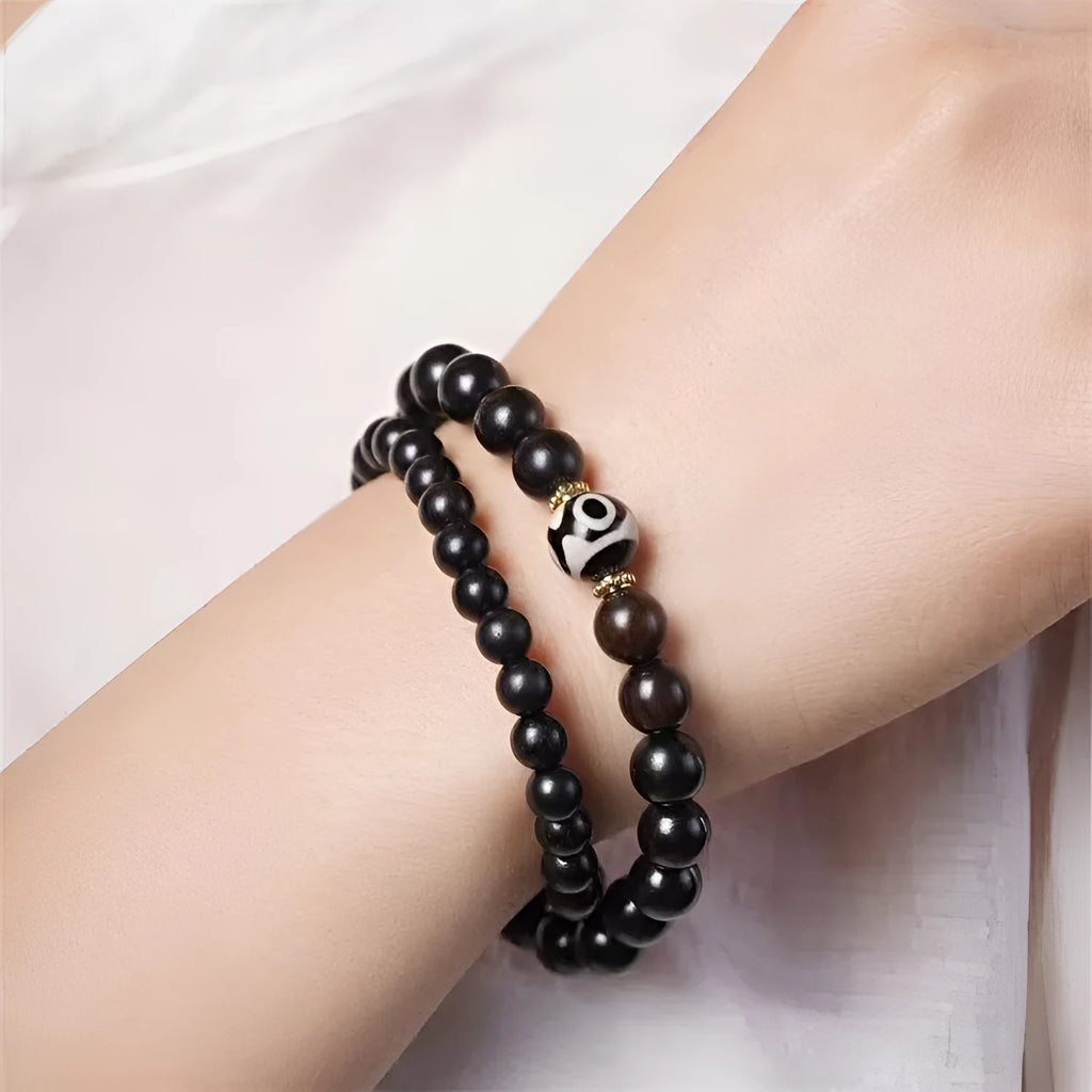 Dark ebony wood bracelet with 8mm beads in a two-circle Tibetan style on a wrist.