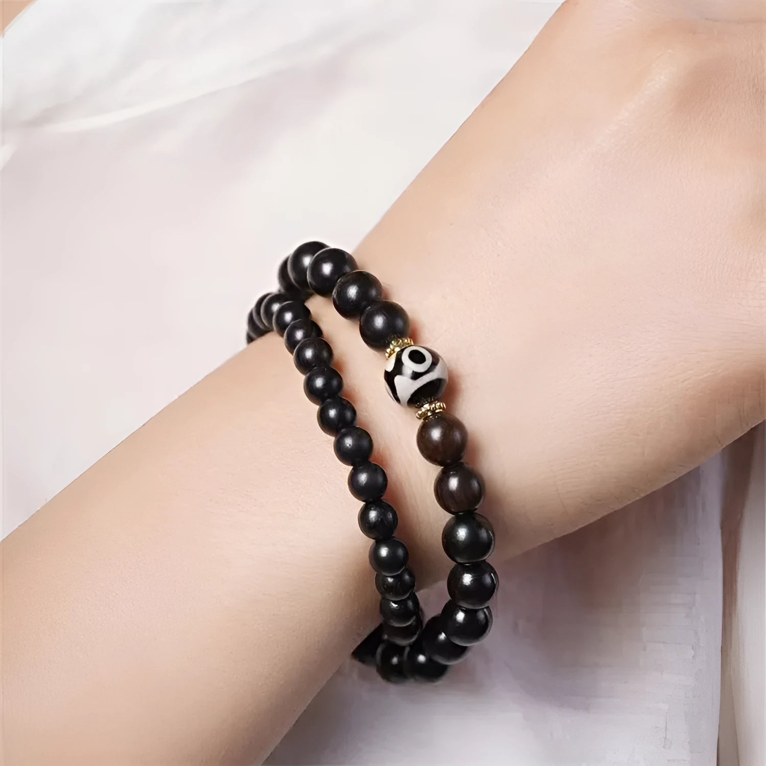 Dark ebony wood bracelet with 8mm beads in a two-circle Tibetan style on a wrist.