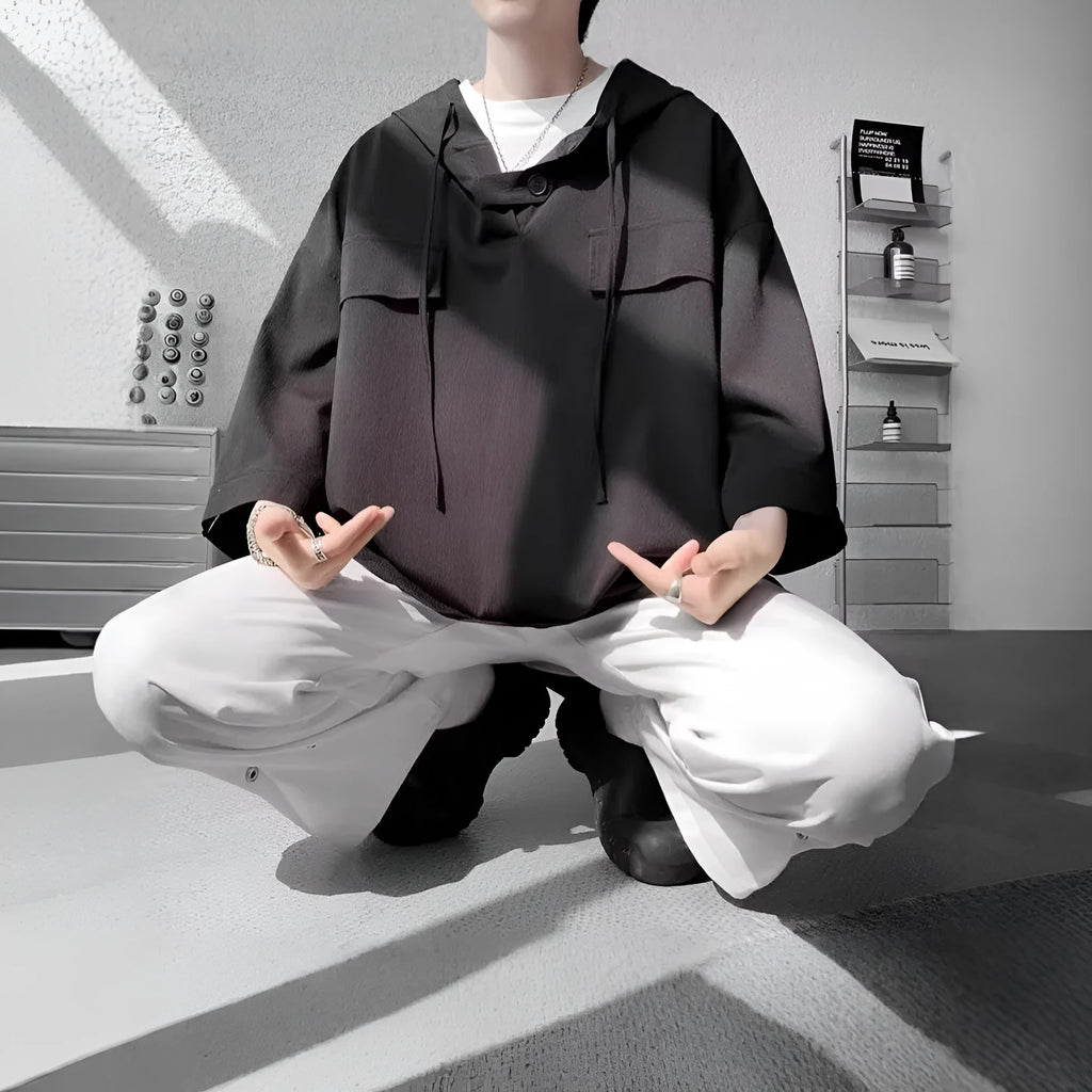 Man wearing a loose black hooded short sleeve t-shirt, a summer casual pullover top.
