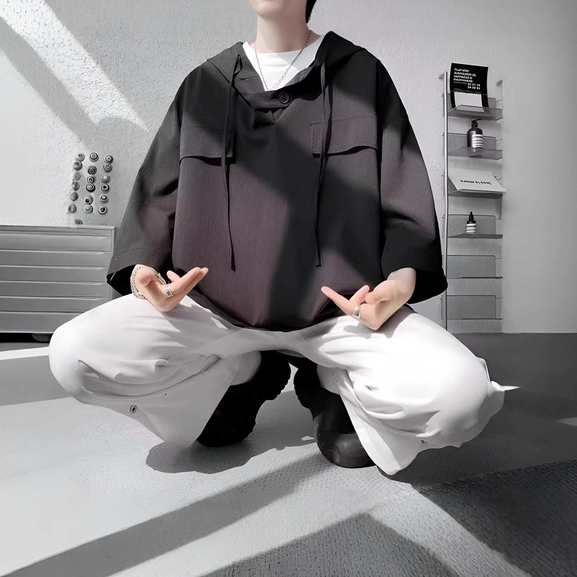 Man wearing a loose black hooded short sleeve t-shirt, a summer casual pullover top.