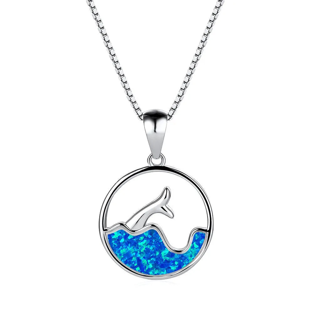 Close-up of a women's geometric fishtail necklace with a round blue opal pendant on a white gold-coloured chain.