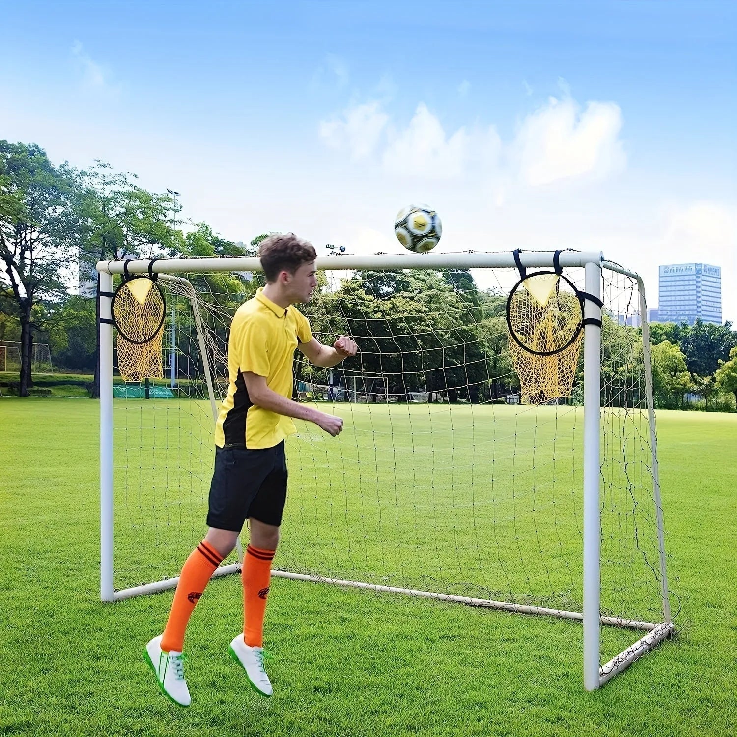 A portable black and yellow soccer training goal net with a steel frame set up on grass.