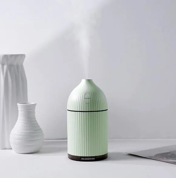 White ultrasonic aromatherapy diffuser humidifier with USB cable and LED light on wooden table