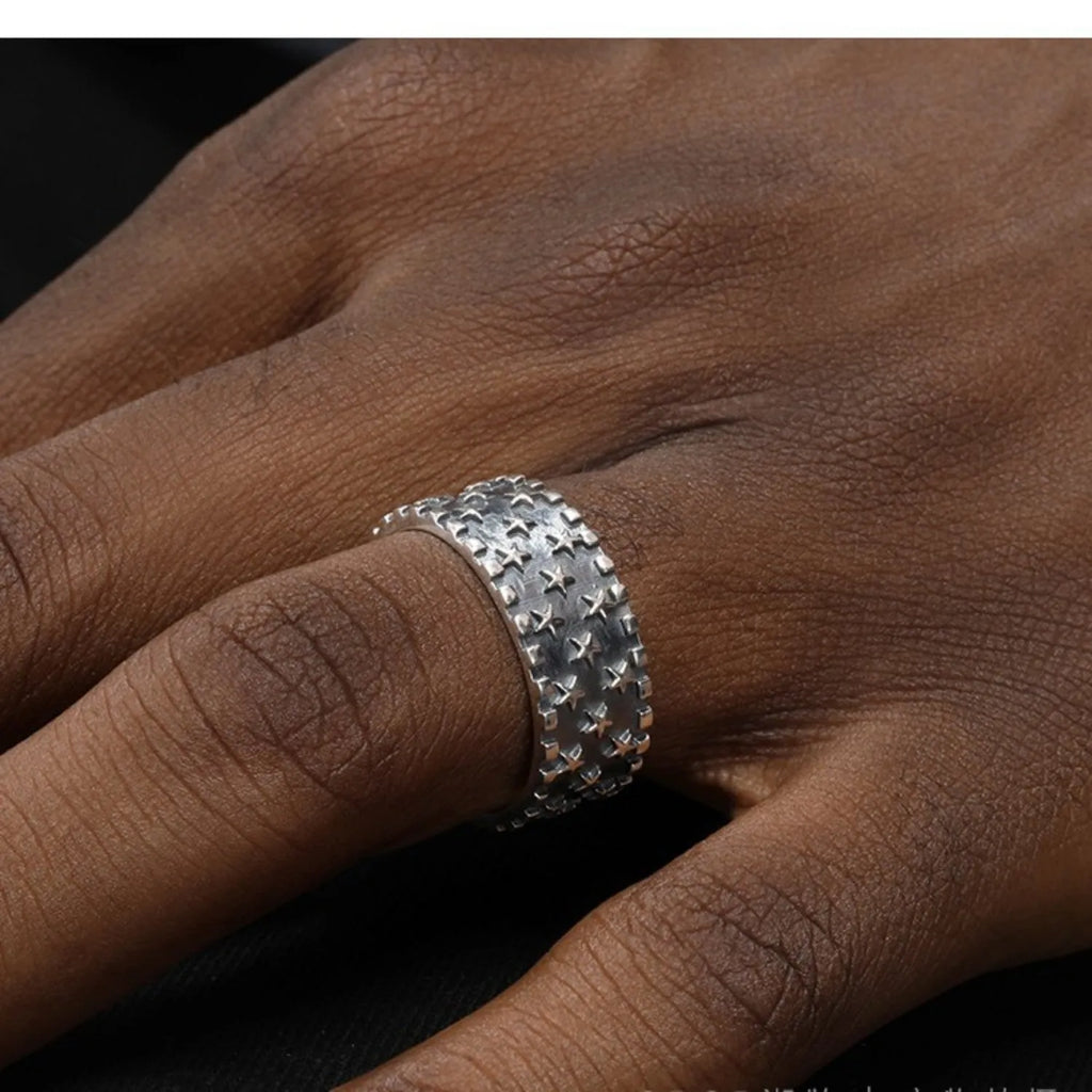 Close-up of an adjustable silver ring with a geometric multi five-pointed star design on a neutral background.