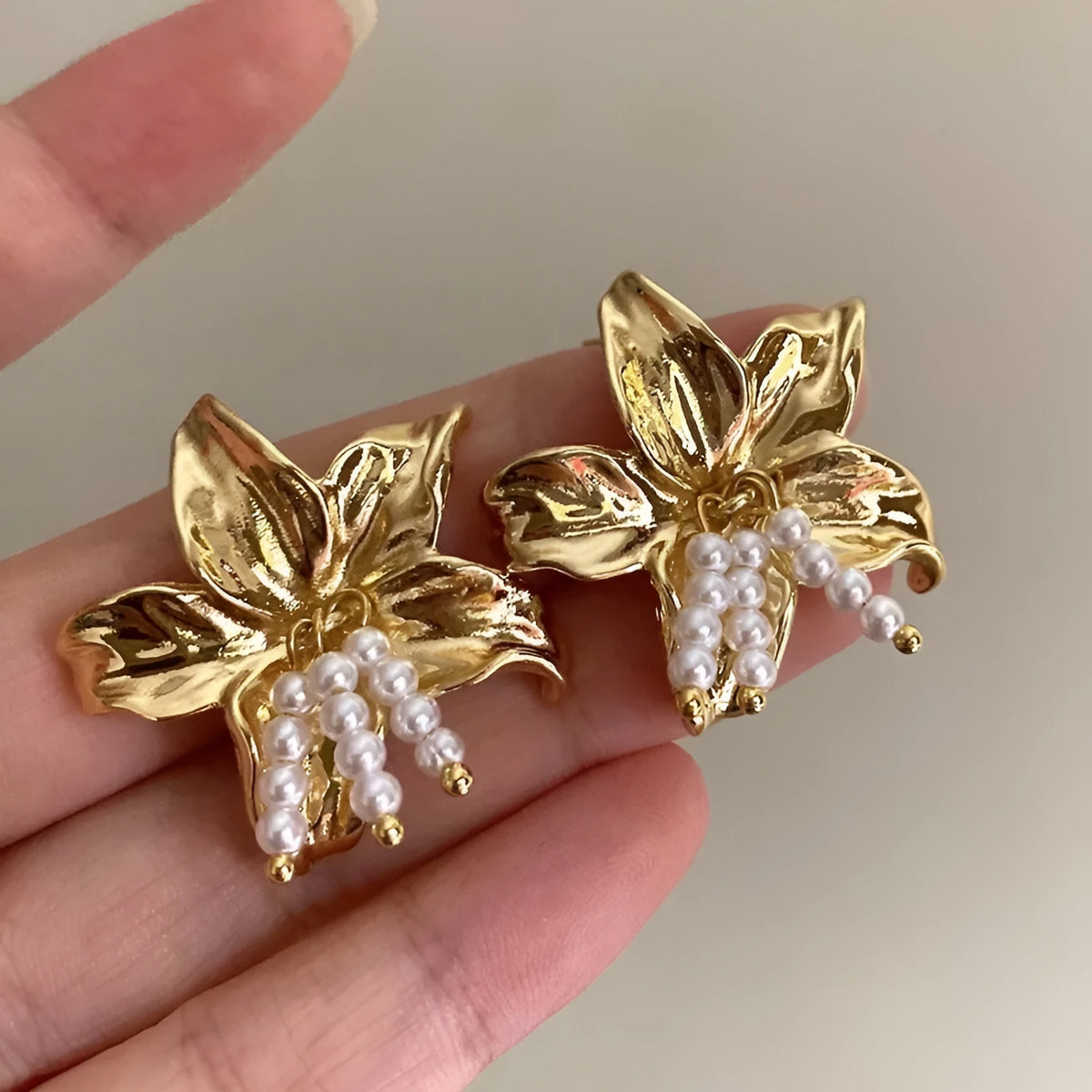 Gold H1795 pearl flower earrings with floral design on a white background.