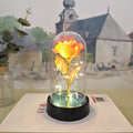 Small decorative night lamp with glass cover and plastic flowers, showing coloured light illumination.