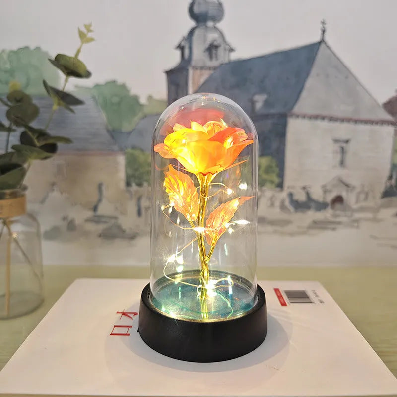 Small decorative night lamp with glass cover and plastic flowers, showing coloured light illumination.