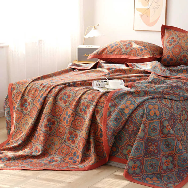 Cotton gauze floral blanket and two pillowcases set laid on a bed, showing plants and flowers pattern.