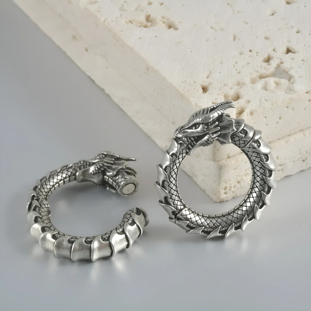 Close-up of large geometric dragon silhouette hollow out alloy earrings in antique silver finish.