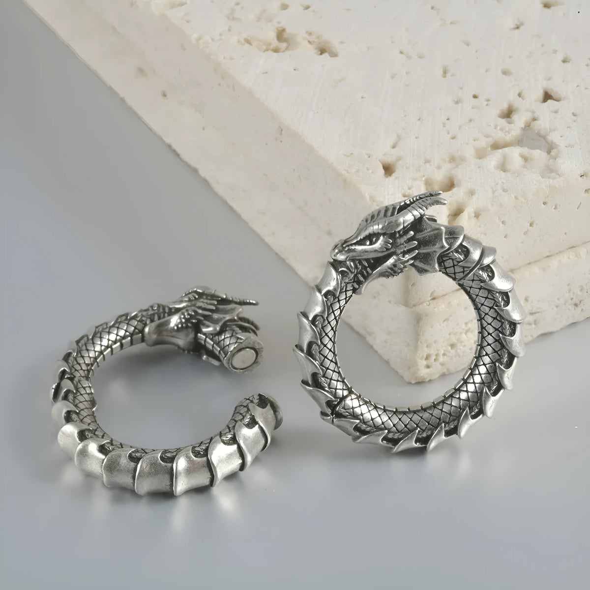 Close-up of large geometric dragon silhouette hollow out alloy earrings in antique silver finish.
