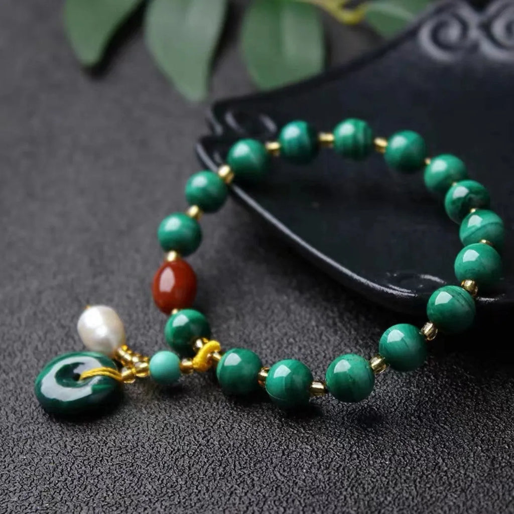 Handmade natural malachite and red agate stone bead bracelet on a wrist.
