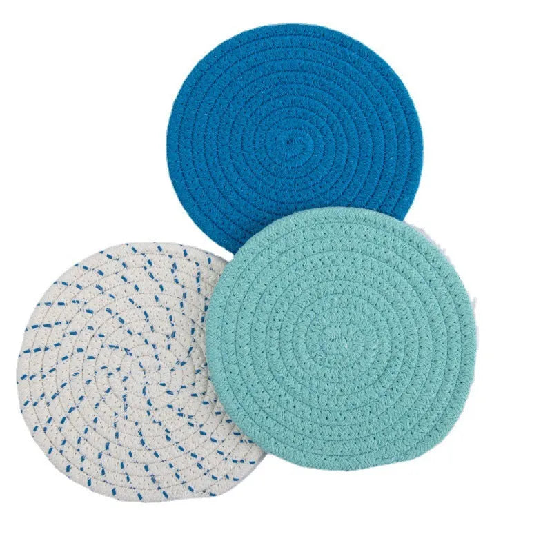 Three round cotton cord coasters in blue colour set on wooden table