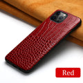 Handmade leather iPhone case with a crocodile pattern in multiple colours on a table.